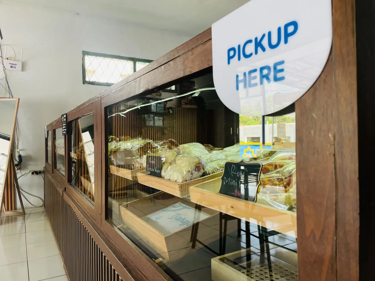 Rak ambil pesanan bertuliskan Pickup Here